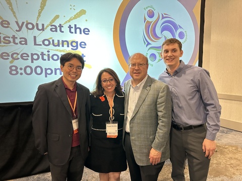 Four people standing in front of a welcome sign for a scientific conference